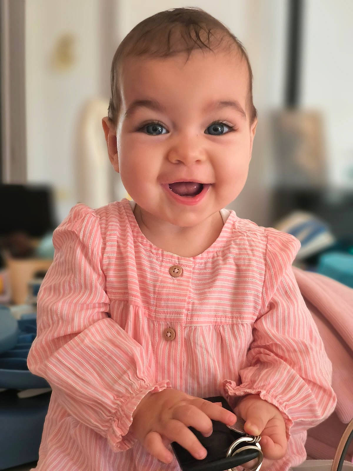 baby, bright_eyes, buttoned, cheerful, child, closeup, cute, face, hands, happy, holding, indoor, keys, long_sleeves, person, pink_dress, portrait, smiling, soft_background, young_child