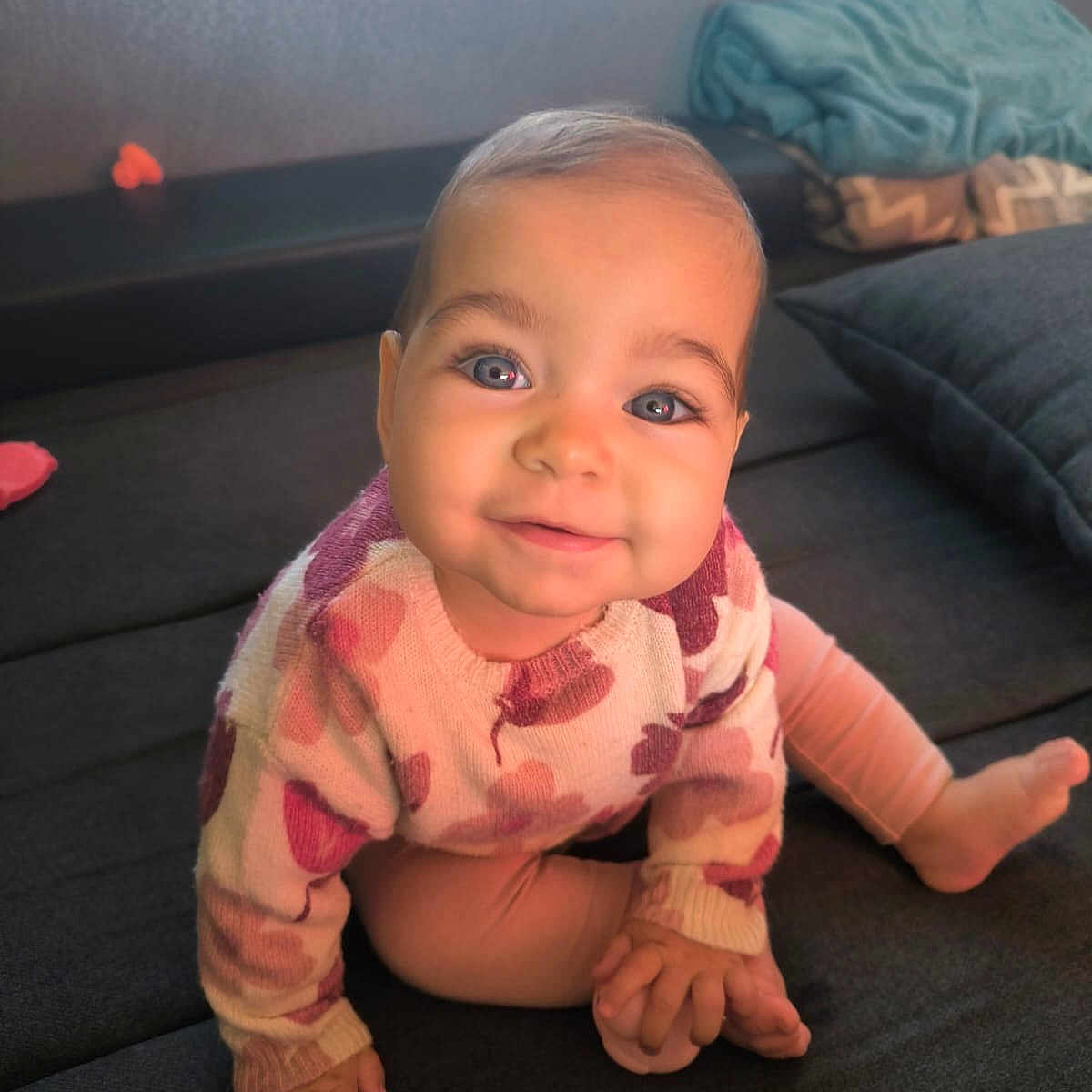 Lyana a rejoint le concours — aidez-le/la à gagner de superbes lots ! baby, blue_eyes, child, couch, cozy, cushion, cute, face, foot, hand, happy, indoor, pink, portrait, purple, sitting, smiling, soft_lighting, sweater, toy