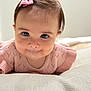 baby, child, face, pink_bow, knitted_sweater, close_up, curious_expression, soft_surface, indoor, portrait, cute, infant, young_child, skin, hair, eyes, head, person, smile, crawling
