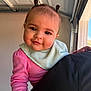 Rosalynn is registered to the contest to win money with this photo: baby, child, person, face, smile, pink_clothing, bib, hair_ties, indoors, shoulder, closeup, natural_light, cute, infant, expression, portrait, human, skin, head, warm