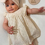 Rosalynn is registered to the contest to win money with this photo: baby, infant, girl, headband, bow, dress, white_background, wooden_plaque, three_months, smiling, cute, portrait, lying_down, fabric_texture, milestone, child, small_hands, soft_lighting, happy, face