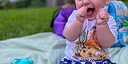Dexter is registered to the contest to win money with this photo: baby, child, smiling, happy, outdoor, grass, blanket, shorts, shirt, toy, playtime, summer, cute, clapping, blue_eyes, head, person, sitting, expression, fun
