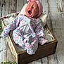 baby, newborn, yawning, headband, floral_onesie, wooden_box, blanket, floor, greenery, soft_lighting, cozy, infant, sleepy, portrait, indoors, cute, pink, white, decor, resting