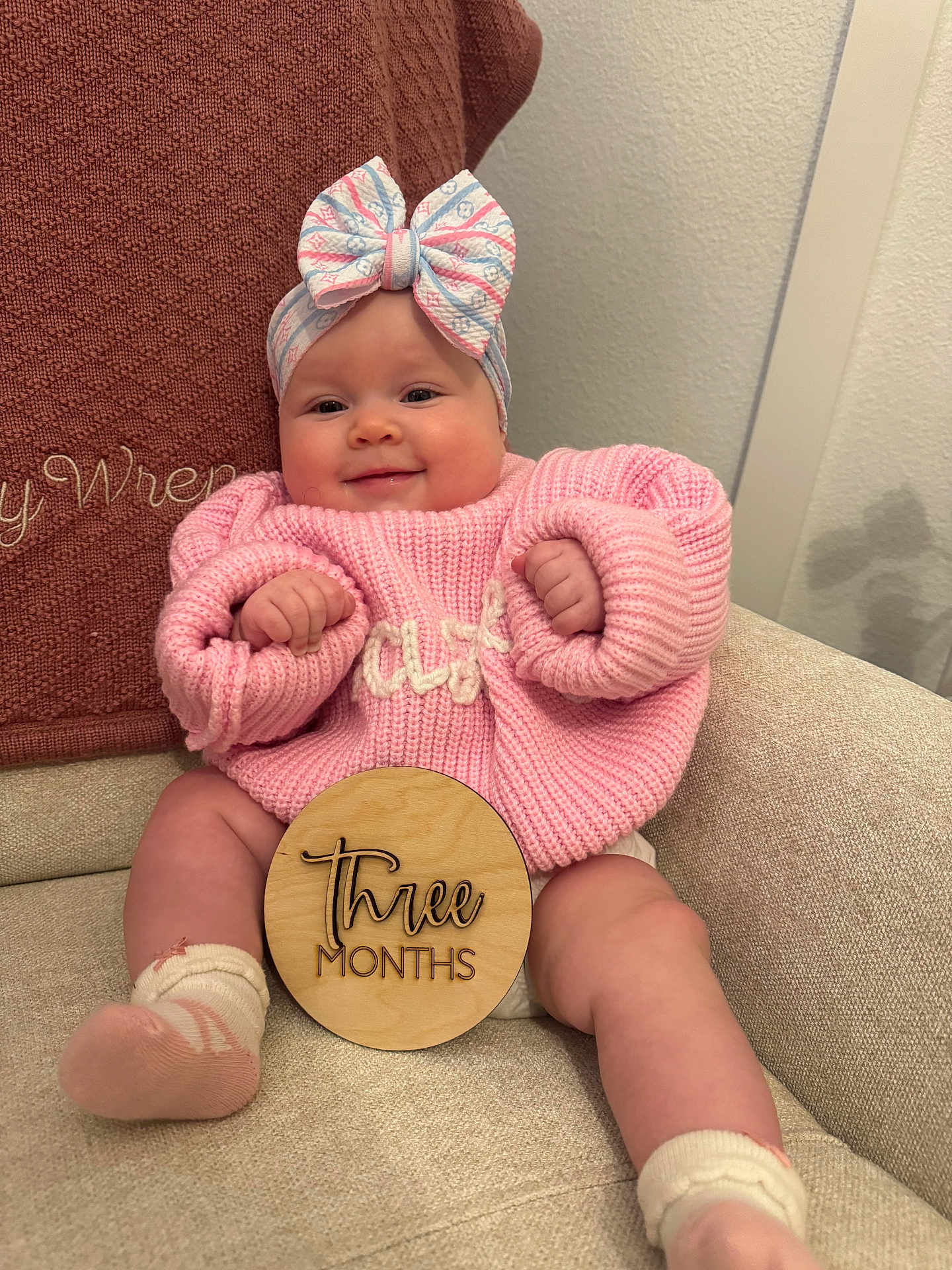 Hazley joined the competition — help win amazing prizes! baby, infant, smile, pink_sweater, headband, bow, wooden_sign, three_months, milestone, couch, blanket, cozy, cute, chubby_cheeks, socks, indoor, portrait, child, happy, seated