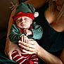 Marceau a rejoint le concours — aidez-le/la à gagner de superbes lots ! baby, infant, sleeping, child, woman, adult, holding, hands, christmas_outfit, elf_hat, striped_pants, red_and_green, cozy, indoor, couch, portrait, holiday, smile, love, family