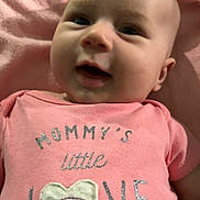 Alina is registered to the contest to win money with this photo: baby, infant, pink_onesie, smiling, face, closeup, text_on_clothing, blanket, cute, child, portrait, apparel, fabric, happy, young, person, indoors, soft, toddler, love