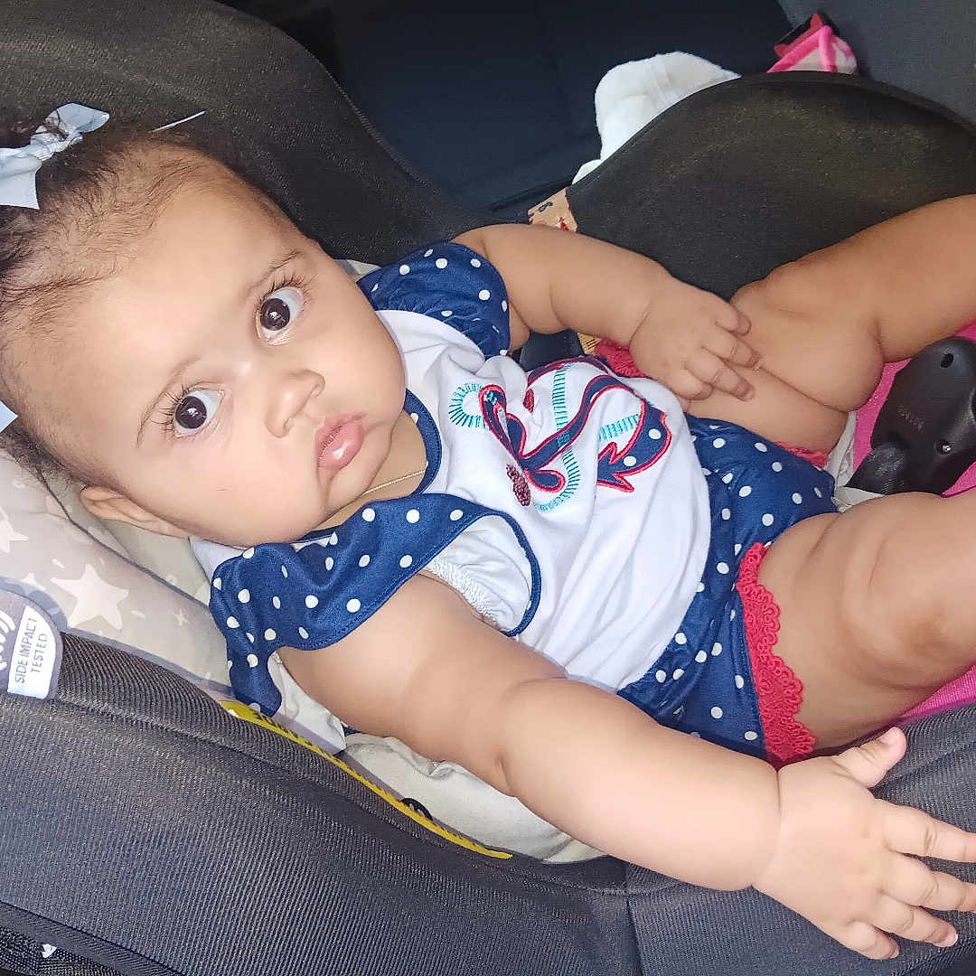 Mikayla Davidson is registered to the contest to win money with this photo: baby, infant, child, car_seat, portrait, sitting, lying_down, wide_eyes, facial_expression, bow, hair_bow, polka_dots, dress, red_shoes, shoes, pink, vehicle_interior, car, indoors, close_up