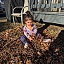 toddler, child, autumn_leaves, outdoor, play, curly_hair, long_sleeve_shirt, pants, shoes, backyard, chair, grill_cover, porch, sunlight, shadow, grass, dirt, daytime, casual, sitting