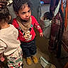 Azariah is registered to the contest to win money with this photo: child, toddler, indoor, clothing, mickey_mouse, curly_hair, boots, pants, sweater, bib, backpack, carpet, chair, coat, bag, toy, person, curious, standing, home