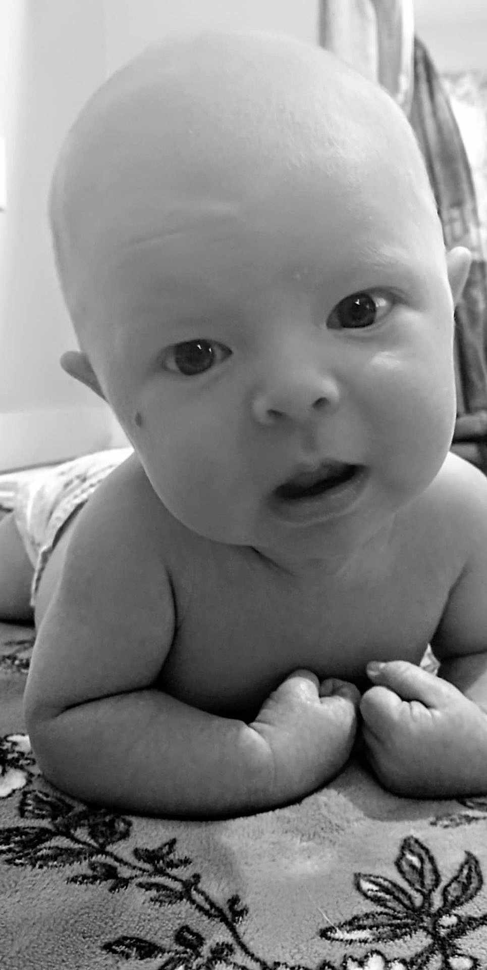 Zoey is registered to the contest to win money with this photo: baby, infant, close_up, black_and_white, face, eyes, hands, blanket, indoor, curious, skin, head, expression, child, toddler, lying_down, portrait, young, cute, person