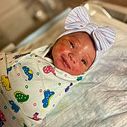 Janiyla is registered to the contest to win money with this photo: newborn, baby, infant, swaddled, blanket, headband, bow, hospital, bed, sleeping, cute, colorful, pattern, dinosaur, soft, child, portrait, indoors, person, newborn_baby