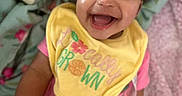 Janiyla joined the competition — help win amazing prizes! baby, smiling, happy, child, infant, bib, pink_clothing, yellow_bib, blanket, soft, indoors, cute, joyful, portrait, sitting, face, human, young_child, expressive, cheerful