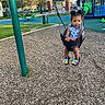 Janiyla is registered to the contest to win money with this photo: blue_dress, butterfly_decor, child, clouds, curious_expression, daylight, grass, green_slide, hair_buns, metal_chains, outdoor, park, play_equipment, playground, shoes, sky, swing, toddler, trees, woodchips