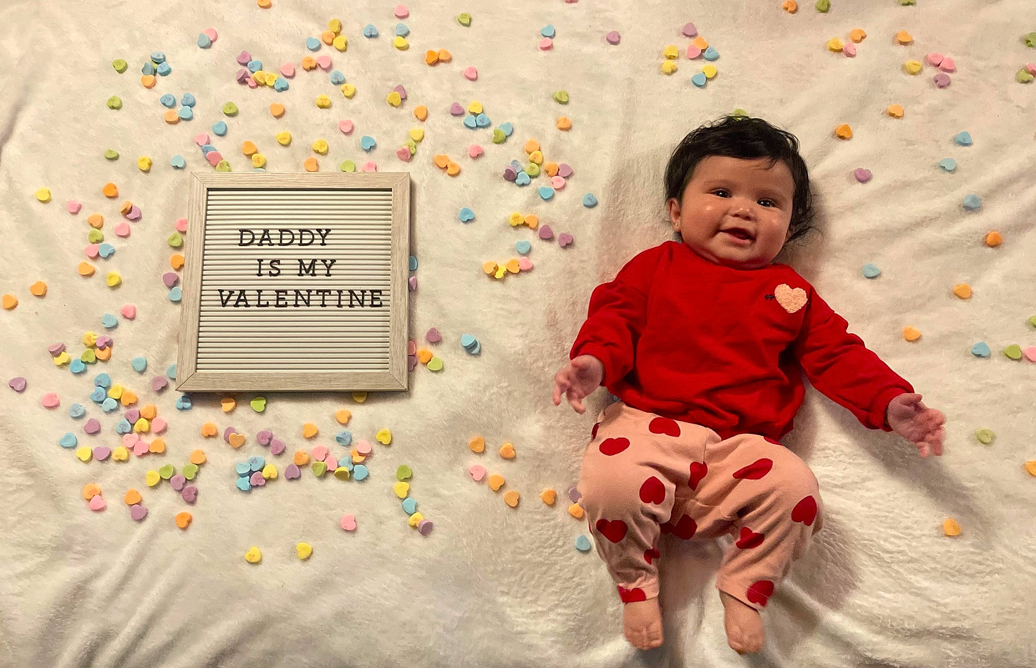 Lily is registered to the contest to win money with this photo: baby, baby_toddler_clothing, child, circle, event, face, font, fun, happy, party_supply, pattern, people, people_in_nature, person, play, room, sitting, sleeve, t_shirt, textile