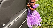 Jaior Milani joined the competition — help win amazing prizes! child, toddler, purple_dress, grass, car_door, outdoor, sunlight, portrait, cute, determined, young_girl, fashion, feet, hair_bows, expression, people, daylight, wall, sidewalk, shoes