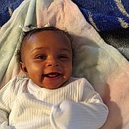 Treasure is registered to the contest to win money with this photo: baby, smiling, pajamas, blanket, infant, cute, happy, child, lying_down, soft_texture, indoors, cozy, face, young_child, white_clothing, portrait, adorable, small_child, head, comfort