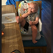 Nikolai joined the competition — help win amazing prizes! baby, high_chair, table, food, foot, chair, towel, blue, indoor, wooden_table, cutting_board, floor, door, light, child, casual, eating, person, home, kitchen