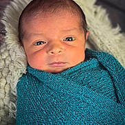 Zaylen is registered to the contest to win money with this photo: baby, blanket, child, closeup, cozy, cute, expression, face, indoors, infant, knit, newborn, person, portrait, resting, soft, teal, texture, wrapped, young
