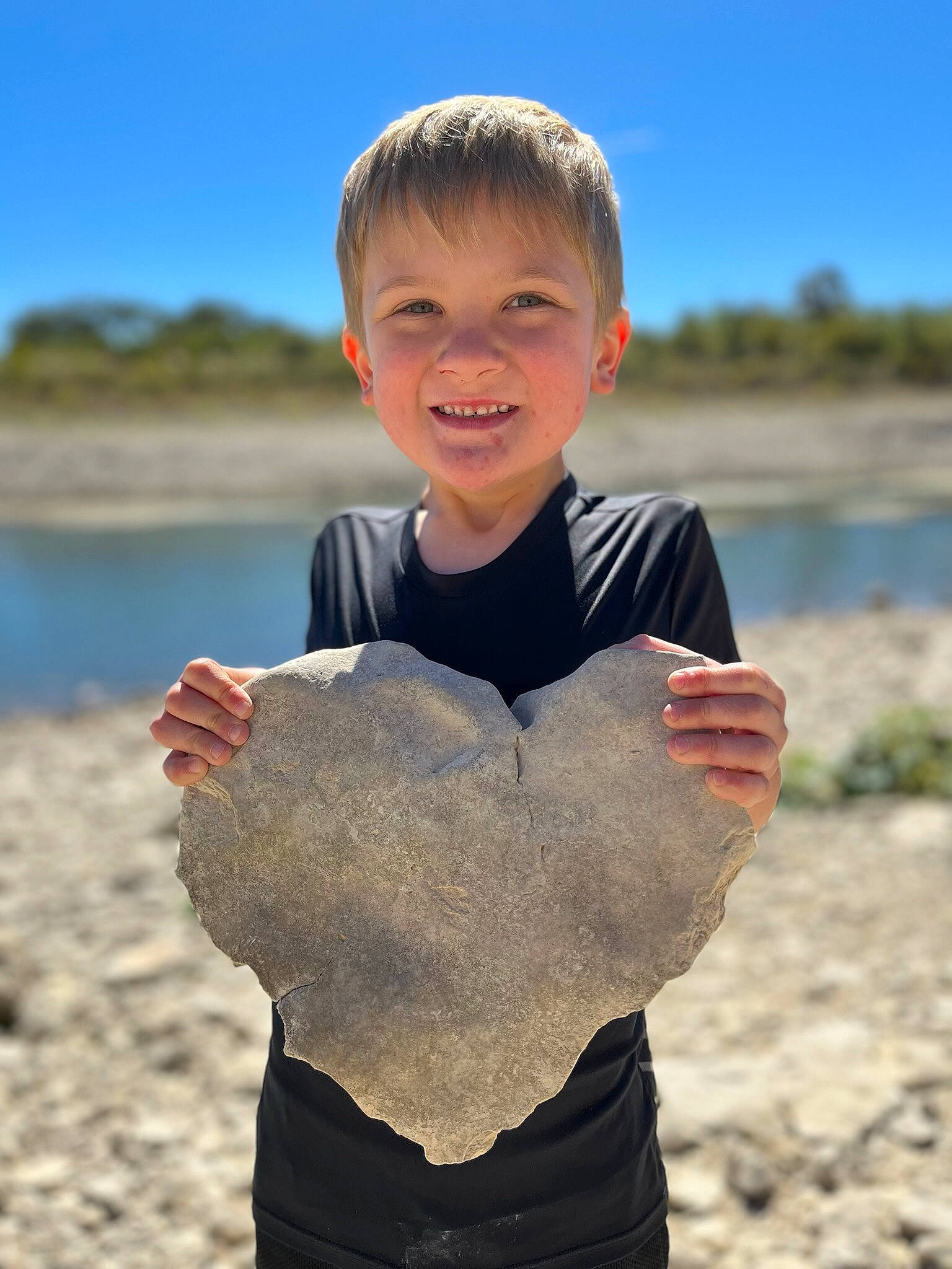 Kristofer is registered to the contest to win money with this photo: beach, child, finger, flash_photography, fun, gesture, grass, happy, landscape, people_in_nature, person, sand, sky, sleeve, smile, soil, t_shirt, thumb, toddler, travel