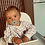 Anna participe au concours pour gagner de l'argent avec cette photo : toddler, pacifier, high_chair, clothing, sweater, baby, indoor, kitchen, furniture, person, child, face, hands, expression, cute, small_object, brown_hair, earrings, wooden_slats, appliance
