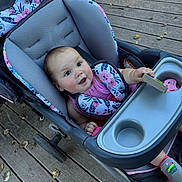 Kehlani joined the competition — help win amazing prizes! baby, stroller, child, toy, wooden_deck, leaves, pink_clothing, floral_pattern, sneakers, seat_belt, outdoor, happy, smiling, infant, person, face, hand, footwear, playful, daylight