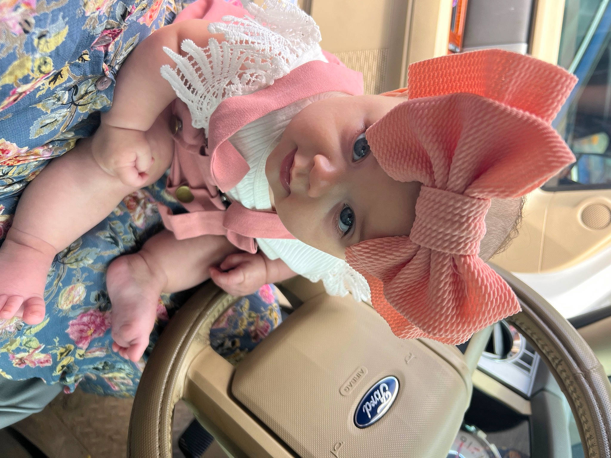 Caroline is registered to the contest to win money with this photo: automotive_design, baby, baby_products, car_seat, child, dress, eye, facial_expression, fun, happy, hat, head, headwear, motor_vehicle, mouth, person, pink, seat_belt, skin, steering_wheel