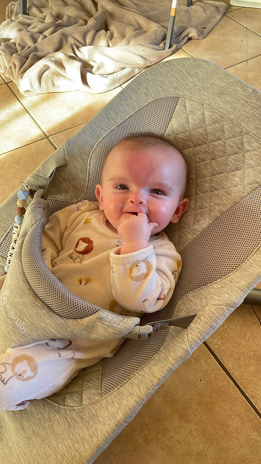 Eloann participe au concours pour gagner de l'argent avec cette photo : baby, baby_accessory, baby_clothing, baby_seat, blanket, child, comfort, cozy, cute, face, fingers_in_mouth, floor_tiles, happy, home, indoor, infant, natural_light, person, relaxed, smiling