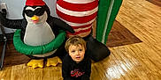 Carter joined the competition — help win amazing prizes! black_hoodie, boy, child, cute, decorations, festive, floor, green, holiday, indoor, inflatable, penguin, radiator, red, santa_claus, sneakers, toy, wall, white, wooden_floor