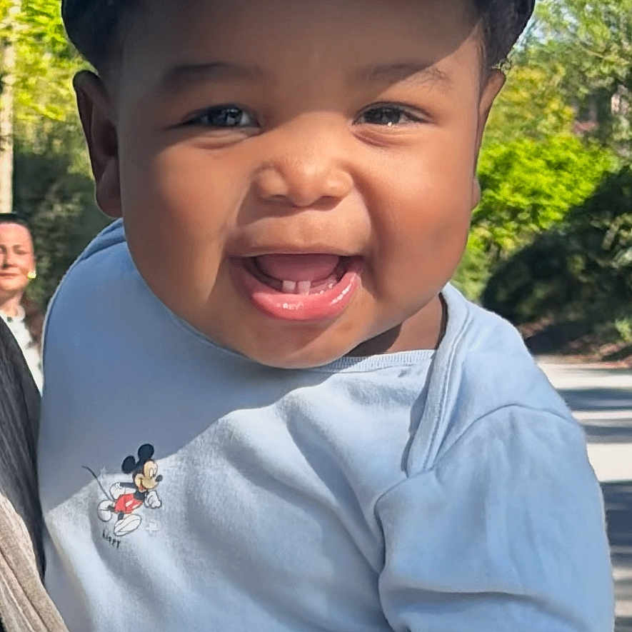 Lyam-Rafaël participe au concours pour gagner de l'argent avec cette photo : baby, child, smiling, cap, blue_shirt, mickey_mouse, outdoor, daylight, nature, trees, person, cute, happy, infant, park, sunlight, holding, portrait, face, clothing