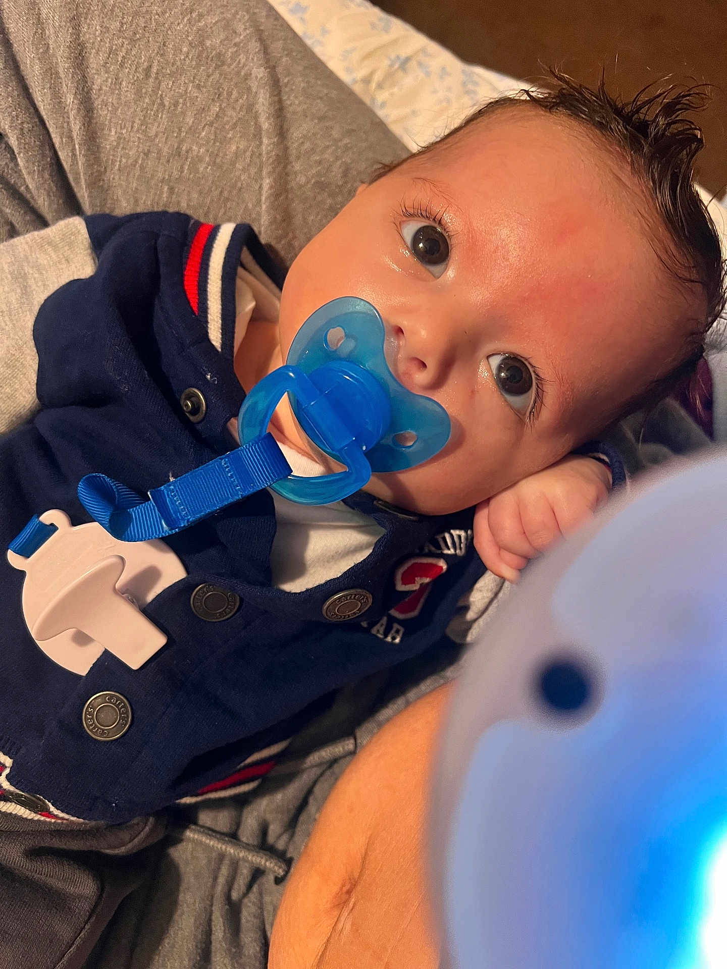 Amariyon is registered to the contest to win money with this photo: baby, pacifier, blue, face, infant, eyes, clothing, hand, person, closeup, skin, hair, button, fabric, comfort, resting, indoor, cute, portrait, child