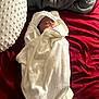 Kyantae is registered to the contest to win money with this photo: baby, blanket, bed, white_towel, pillow, red_bedspread, gray_blanket, infant, wrapped, lying_down, soft_texture, cozy, face, newborn, indoors, cute, sleepwear, resting, comfort, small