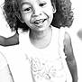 black_and_white, casual_clothing, child, close_up, curly_hair, cute, earrings, expression, face, happy, headband, indoor, joyful, person, playful, portrait, smiling, tank_top, toddler, young