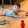 baby, child, toy, floor, wooden_floor, indoor, crawling, curious, cute, infant, playtime, person, blue_outfit, wood, furniture_leg, small_toy, red_toy, zebra_toy, bright_colors, young_child