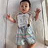 David joined the competition — help win amazing prizes! baby, crib, infant, child, suspenders, plaid_shorts, white_shirt, sign, text, looking_up, wide_eyes, open_mouth, mesh_sides, mattress, indoor, cute, young_child, caucasian_baby, person, lying_down
