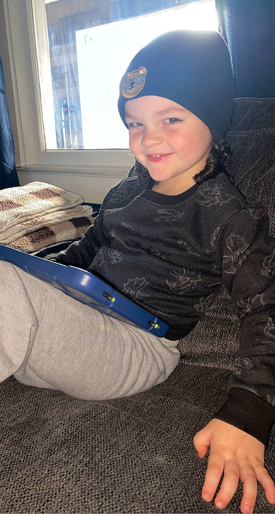 River joined the competition — help win amazing prizes! beanie, cap, child, comfort, cool, electric_blue, fashion_accessory, fun, happy, headwear, human_leg, joy, knee, lap, pattern, person, personal_protective_equipment, sitting, sleeve, smile