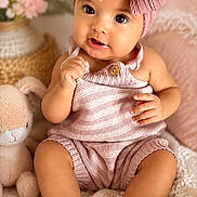 Eliana is registered to the contest to win money with this photo: baby, child, infant, headband, bow, plush_toy, bunny, knitted_blanket, soft_lighting, indoor, cute, smiling, portrait, sitting, clothing, cozy, warm_colors, decor, person, toddler