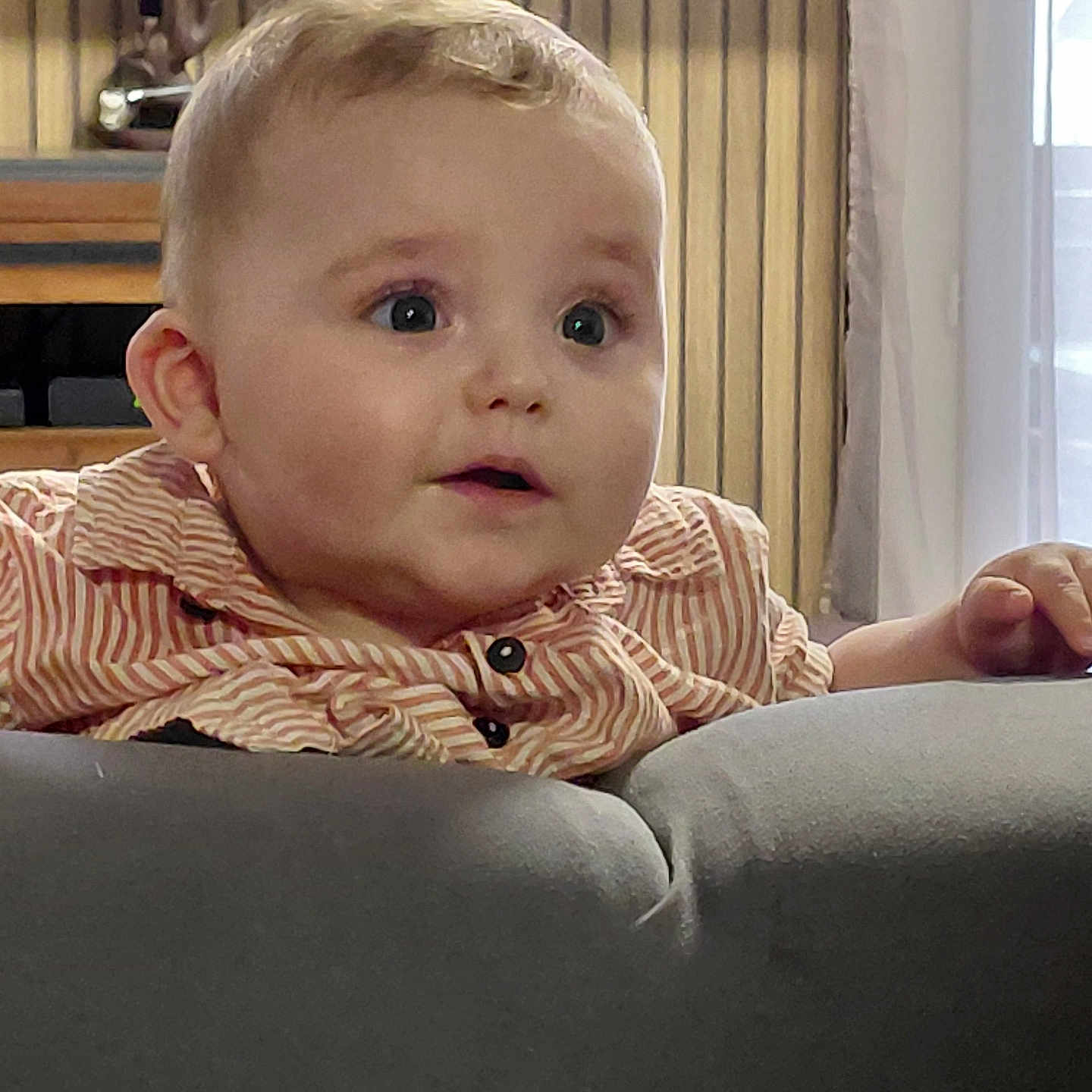 Eden participe au concours pour gagner de l'argent avec cette photo : baby, child, clothing, couch, curious, expression, eyes, face, furniture, hand, head, indoor, light, mouth, person, portrait, skin, striped_shirt, window, young