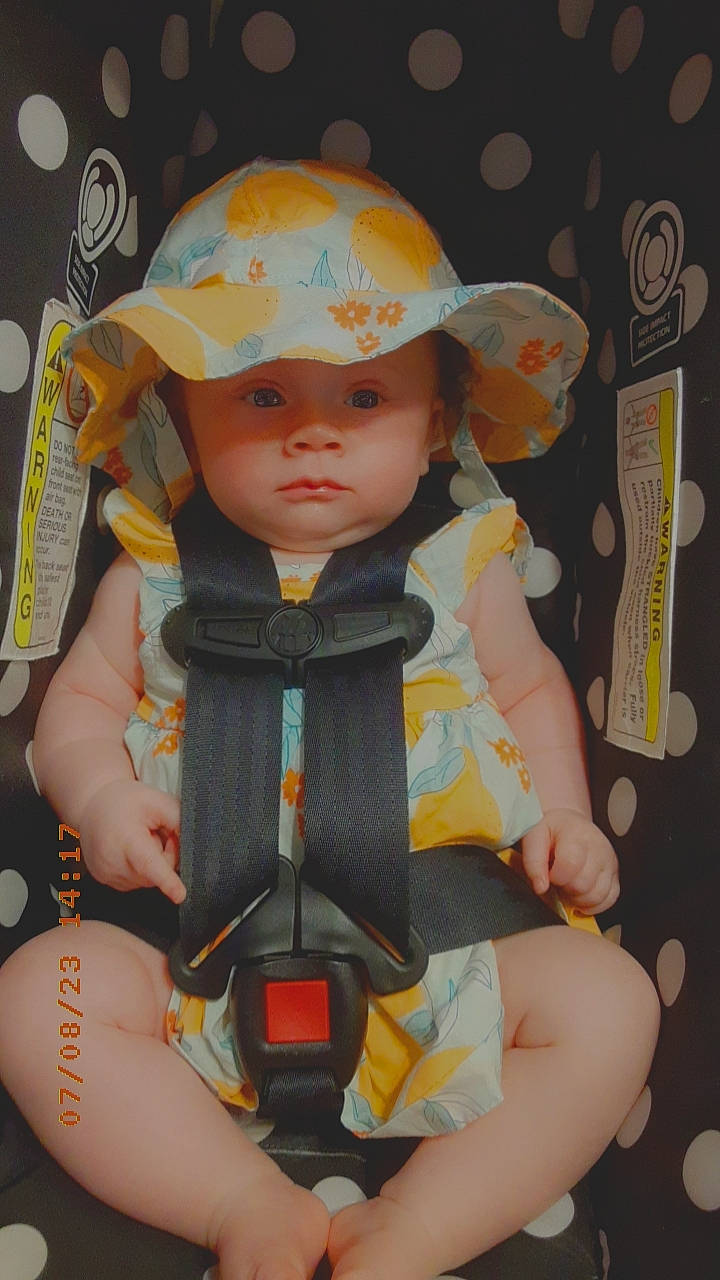 Mazie is registered to the contest to win money with this photo: baby, baby_carriage, baby_products, baby_toddler_clothing, baseball_cap, cap, cheek, child, doll, electric_blue, fashion_accessory, fun, headwear, human_body, person, personal_protective_equipment, sitting, skin, thigh, toddler