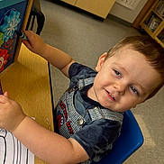 Greyson is registered to the contest to win money with this photo: blue_chair, boy, cabinet, child, classroom, clothing, coloring, face, floor, furniture, hair, indoor, marker, overalls, paper, person, smiling, table, toddler, toy