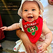 Julia participe au concours pour gagner de l'argent avec cette photo : adult_hand, arm, baby, bandana, cafe, child, cute, dress, face, happy, hat, holding, menu_board, outdoor, person, red, skin, smiling, text_on_bandana, white_clothing