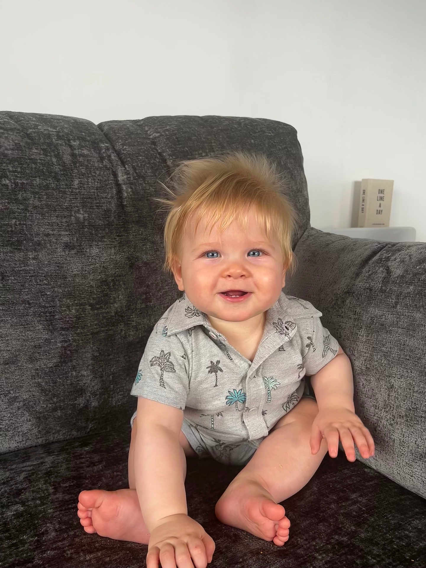Louie joined the competition — help win amazing prizes! baby, child, smiling, blonde_hair, blue_eyes, shirt, palm_tree_pattern, couch, indoor, sitting, cute, happy, portrait, furniture, skin, hand, foot, infant, casual_clothing, home