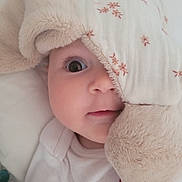 Monica participe au concours pour gagner de l'argent avec cette photo : baby, infant, face, blanket, soft, cute, child, wide_eye, peek, floral_pattern, cuddly, white_clothing, closeup, bed, comfort, adorable, sleepwear, expression, portrait, innocence