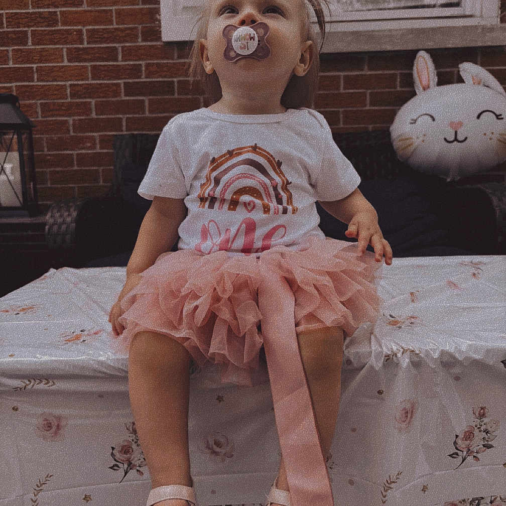 Oaklynn is registered to the contest to win money with this photo: balloon, brick_wall, bunny, child, clothing, curious, cute, decor, face, footwear, outdoor, pacifier, party, pink_tutu, shoes, sitting, table, tablecloth, toddler, window
