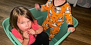 Oaklynn joined the competition — help win amazing prizes! child, children, indoor, plastic_bin, pajamas, floor, wooden_floor, living_room, tv, cabinet, toy, person, sitting, standing, curly_hair, long_hair, orange_clothing, pink_clothing, playful, home