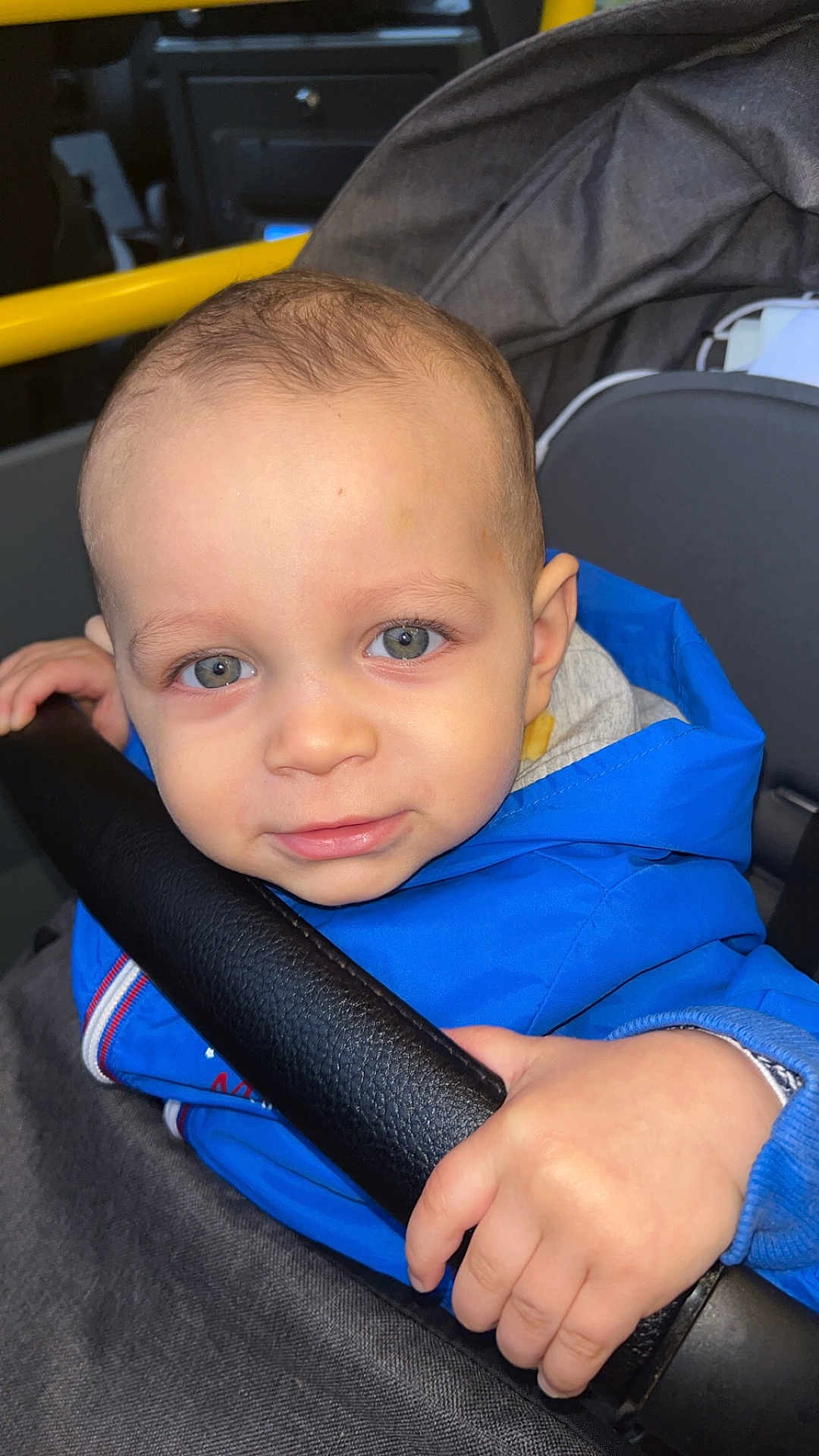 Aaron participe au concours pour gagner de l'argent avec cette photo : toddler, child, blue_jacket, face, hand, stroller, seat, curious, closeup, indoor, person, clothing, skin, eyes, expression, young_child, portrait, baby, casual, grip
