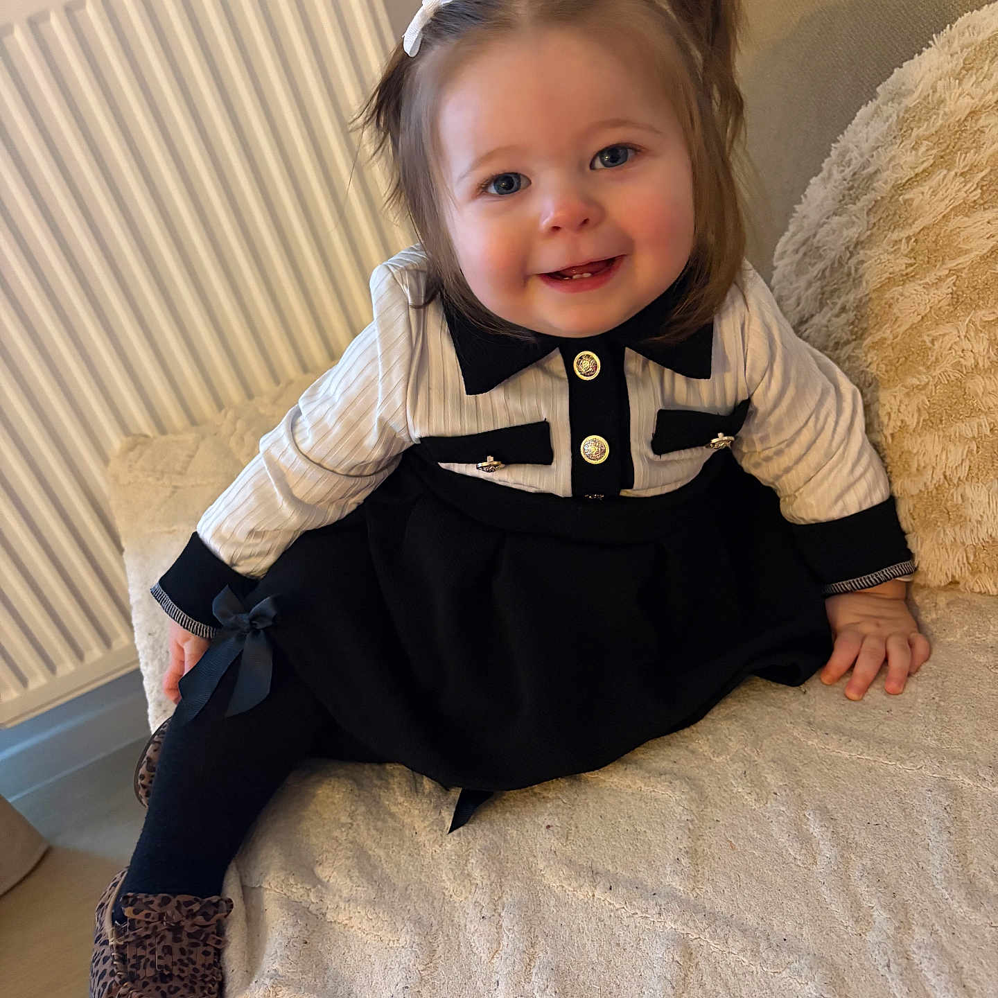 Alma participe au concours pour gagner de l'argent avec cette photo : toddler, child, smile, pigtails, black_and_white_clothing, leopard_print_shoes, couch, beige, cozy, indoor, radiator, cute, happy, portrait, baby, fashion, hand, floor, hair_bow, young