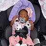 baby, sleeping, car_seat, pacifier, headband, flower, blanket, purple_cushion, pink_clothing, socks, infant, child, safety_harness, seatbelt, pattern, butterfly, soft_toys, resting, cute, newborn