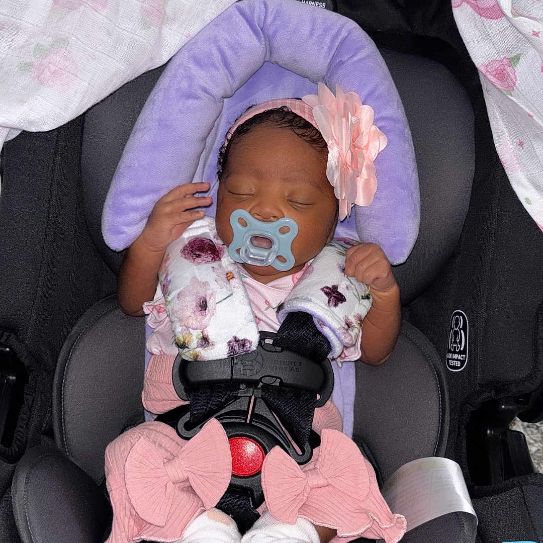 Amari joined the competition — help win amazing prizes! baby, sleeping, car_seat, pacifier, headband, flower, blanket, purple_cushion, pink_clothing, socks, infant, child, safety_harness, seatbelt, pattern, butterfly, soft_toys, resting, cute, newborn