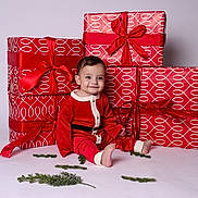 Armen is registered to the contest to win money with this photo: baby, child, red_outfit, santa_costume, presents, gift_wrap, ribbons, holiday, christmas, smile, sitting, greenery, indoor, studio, cute, festive, celebration, holiday_decor, portrait, happy