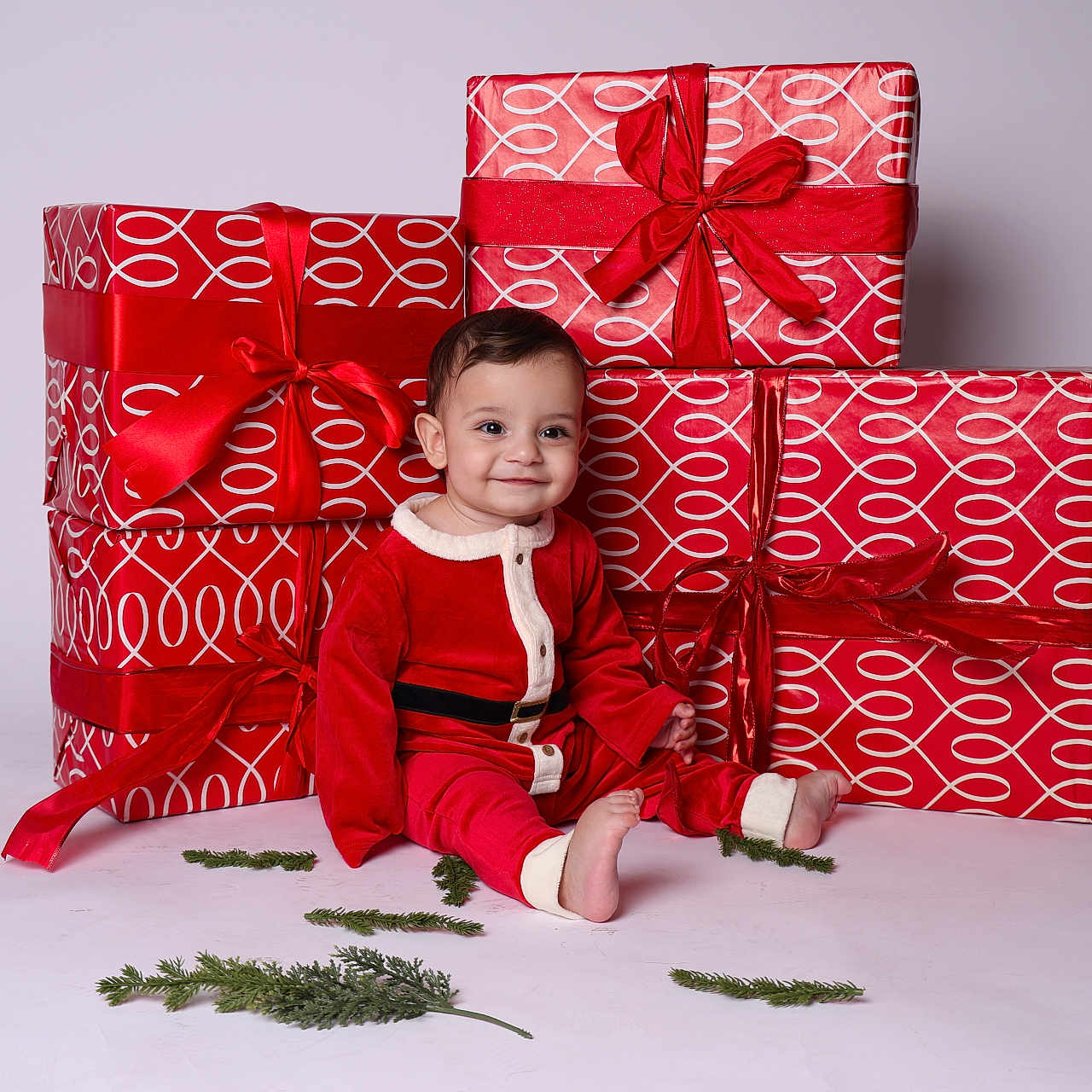 Armen is registered to the contest to win money with this photo: baby, celebration, child, christmas, cute, festive, gift_wrap, greenery, happy, holiday, holiday_decor, indoor, portrait, presents, red_outfit, ribbons, santa_costume, sitting, smile, studio
